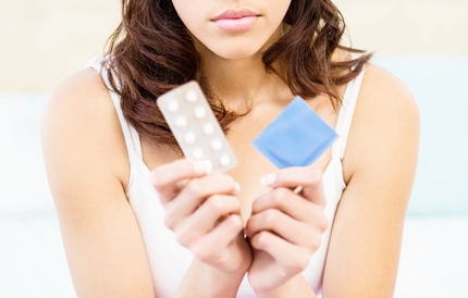 피임약과 콘돔을 들고 있는 여성 