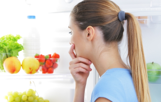 냉장고를 열고 고민하는 여성