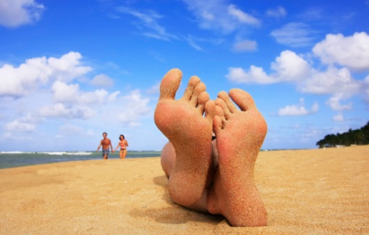 해변에 누워 있는 성인의 발