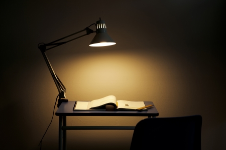 어두운 방에서 책상을 비추는 전등