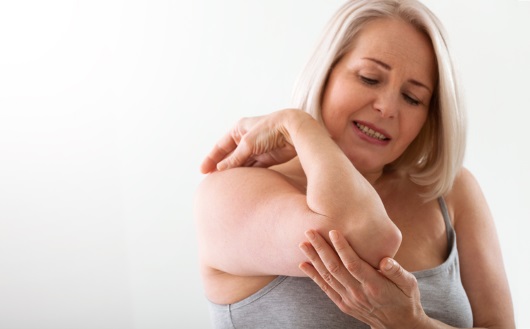 팔꿈치에 통증을 느끼는 여성