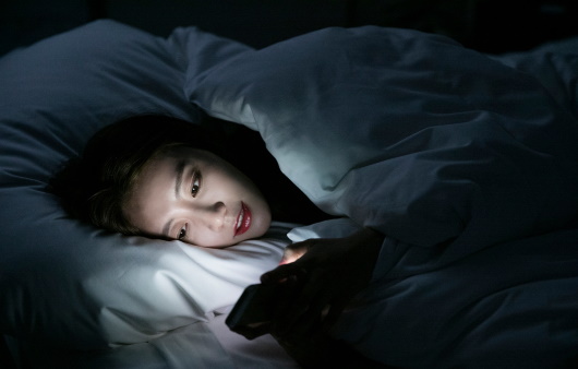 늦은밤 스마트폰을 하면서 누워있는 사람